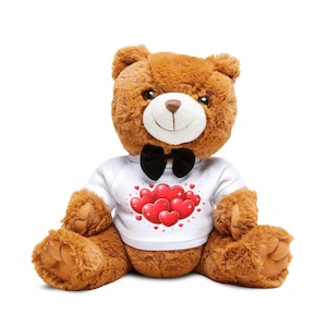 May include: A brown teddy bear with a white t-shirt featuring a cluster of red hearts. The bear has a black bow tie and is sitting upright. The plush toy has a soft, furry texture and is designed for cuddling.