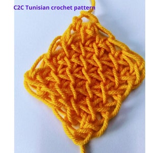 May include: A close-up of a square, yellow Tunisian crochet pattern. The crochet work is made with thick yarn, creating a textured, open weave design. The text "C2C Tunisian crochet pattern" is in the upper left corner.