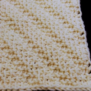 Peut inclure: Un gros plan sur un tissu tricoté de couleur crème. Le tissu est fait d'un fil doux et a une surface texturée.