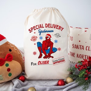 May include: A white canvas Santa sack with a red and blue Spiderman graphic, the text "SPECIAL DELIVERY Spiderman", and the words "FOR: OLIVER Santa Claus APPROVED".