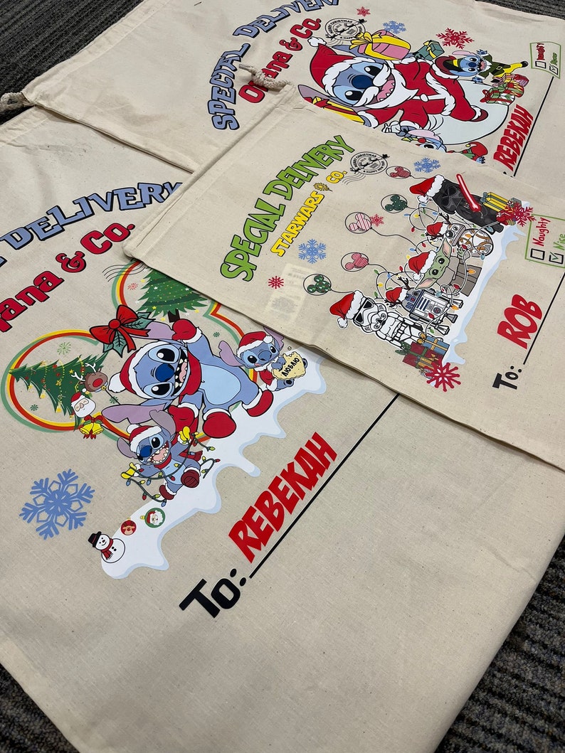 May include: Three white canvas gift bags with colorful designs and the text "Special Delivery" and "Ohana & Co.". The bags have a drawstring closure and are decorated with Christmas-themed characters, including Stitch from Lilo & Stitch, Star Wars characters, and a snowman. The bags have a space for a name and a "To:" label.