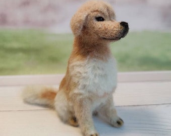 May include: A small, hand-felted golden retriever puppy dog figurine. The dog is sitting with its head tilted to the side and its tail curled behind it. The figurine is made of wool and has a realistic appearance.