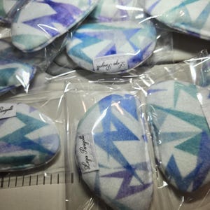 May include: A set of 10 eye pillows with a blue and purple geometric pattern. The pillows are packaged individually in clear plastic bags. Each bag has a label that says "Lega Panggatti".