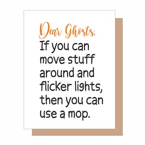 May include: A white greeting card with a tan envelope backing. The text reads in orange script Dear Ghosts, followed by black sans-serif text: If you can move stuff around and flicker lights, then you can use a mop. The design is centered on the card.