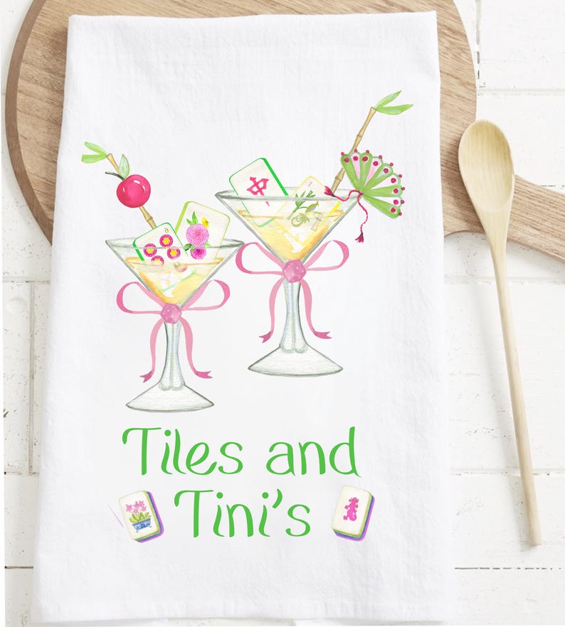 May include: White kitchen towel featuring two martini glasses with Mahjong tiles, pink bows, and decorative garnishes. The towel has the text "Tiles and Tini's" in green. Decorative Mahjong tiles are also shown.