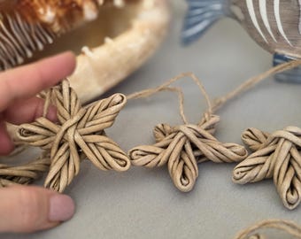 Puede incluir: Adornos de estrella de mar tejidos a mano en tonos beige natural. Cada estrella de mar está intrincadamente elaborada con un diseño tejido y unida a una cuerda de hilo natural. Parte de una colección de temática costera o náutica.