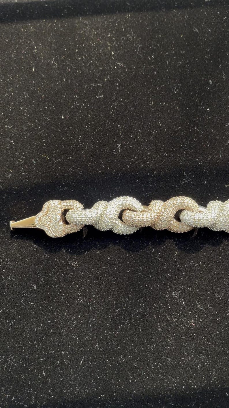 Peut inclure: Un bracelet en or et diamants avec un motif de cha&icirc;ne. Le bracelet pr&eacute;sente une s&eacute;rie de maillons interconnect&eacute;s, chacun incrust&eacute; de petits diamants &eacute;tincelants. Le fermoir est en or et &eacute;galement orn&eacute; de diamants. Le bracelet est pr&eacute;sent&eacute; sur une surface noire.