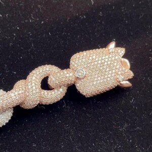 Peut inclure: Bracelet en or rose avec un pendentif en forme de tulipe. Le pendentif et les maillons de la cha&icirc;ne sont incrust&eacute;s de petits cristaux &eacute;tincelants. Le bracelet est pos&eacute; sur un fond sombre, mettant en valeur le design et la couleur des bijoux.