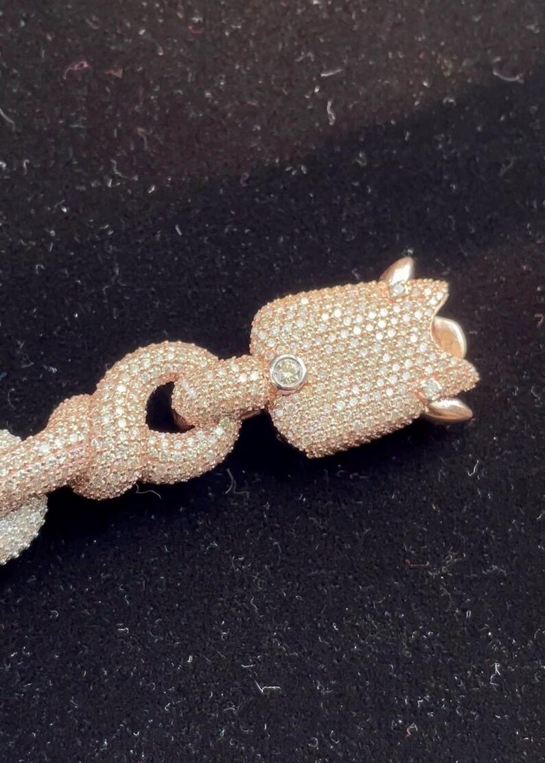 Peut inclure: Bracelet en or rose avec un pendentif en forme de tulipe. Le pendentif et les maillons de la cha&icirc;ne sont incrust&eacute;s de petits cristaux &eacute;tincelants. Le bracelet est pos&eacute; sur un fond sombre, mettant en valeur le design et la couleur des bijoux.