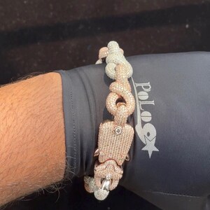 Peut inclure: Un bracelet bicolore avec une finition or rose et argent. Le bracelet pr&eacute;sente un design de maillons unique et est incrust&eacute; de petites pierres scintillantes. Le fermoir est &eacute;galement orn&eacute; de pierres.