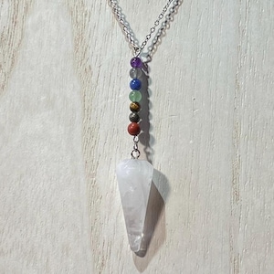 May include: A white crystal pendulum necklace with a silver chain and seven chakra beads in various colors.