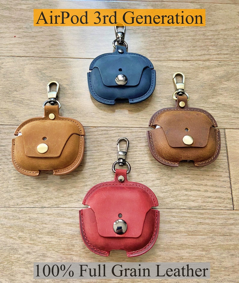 May include: Four leather AirPod 3rd Generation cases with keychains. The cases are in blue, brown, red, and tan. The text "100% Full Grain Leather" is at the bottom of the image.