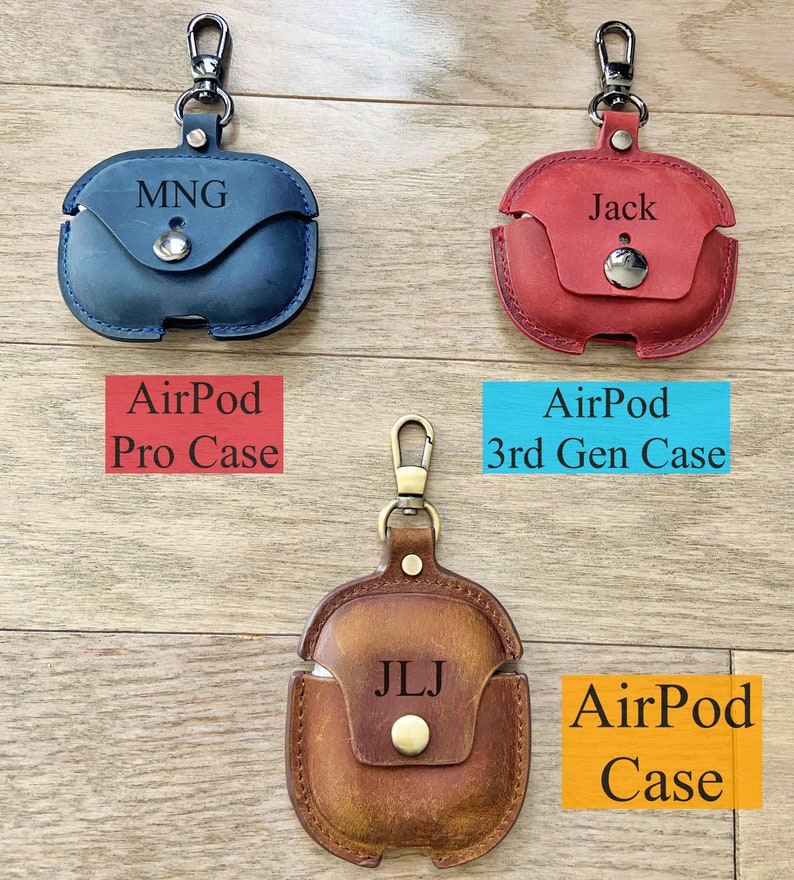 May include: Three leather AirPod cases with personalized initials and a metal carabiner. The cases are blue, red, and brown. The text on the cases reads "AirPod Pro Case", "AirPod 3rd Gen Case", and "AirPod Case".