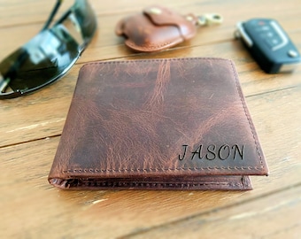 May include: A dark brown leather bifold wallet featuring a textured, distressed finish and visible stitching along the edges. The name JASON is engraved in a clean, sans-serif font on the bottom right corner of the front exterior panel.