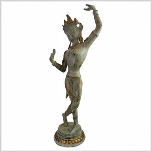 May include: A white and gold painted metal statue of a dancer with a crown and elaborate jewelry. The statue is standing on a round base with a decorative border.