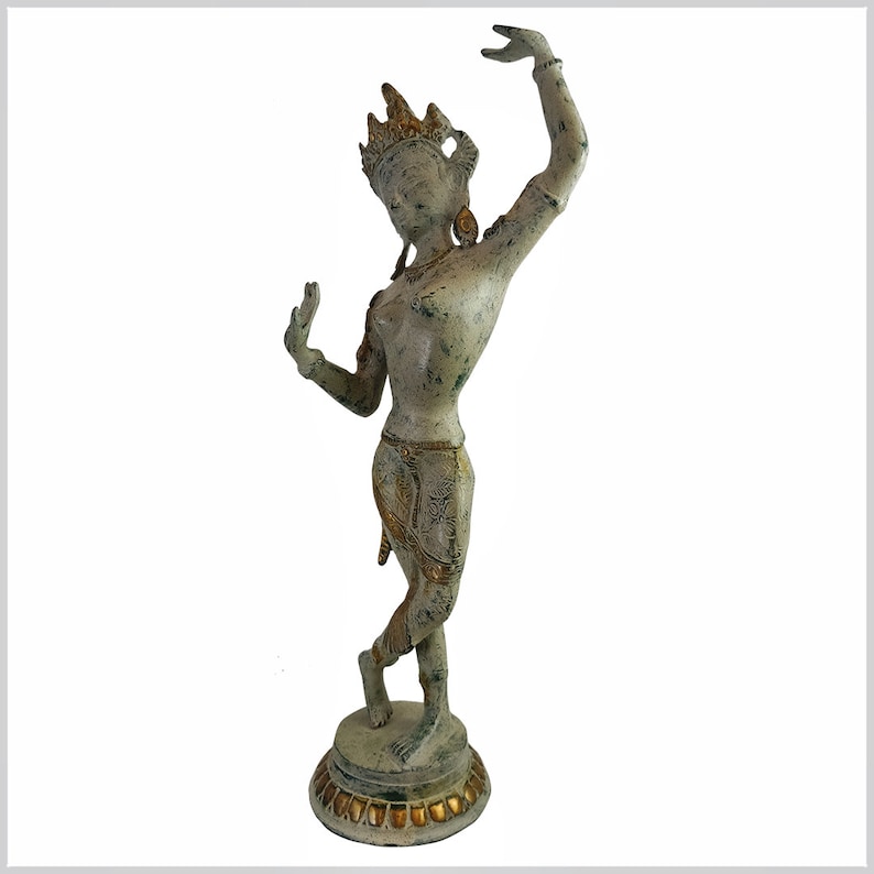 May include: A white and gold painted metal statue of a dancer with a crown and elaborate jewelry. The statue is standing on a round base with a decorative border.
