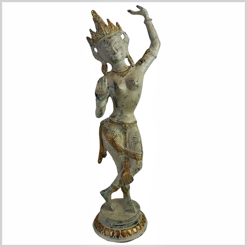 May include: A white and gold metal statue of a dancing woman with a crown on her head. The statue is standing on a round base with a decorative design.