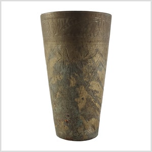 Op de afbeelding: Een drinkglas van messing met een sierlijk, gegraveerd ontwerp. Het glas heeft een conische vorm en een verweerde, verweerde patina.