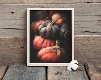 May include: A framed print featuring a collection of pumpkins in various shapes and colors. The pumpkins range from deep orange to muted green, with textured surfaces and prominent stems. The artwork is set against a dark background, enhancing the autumnal theme.