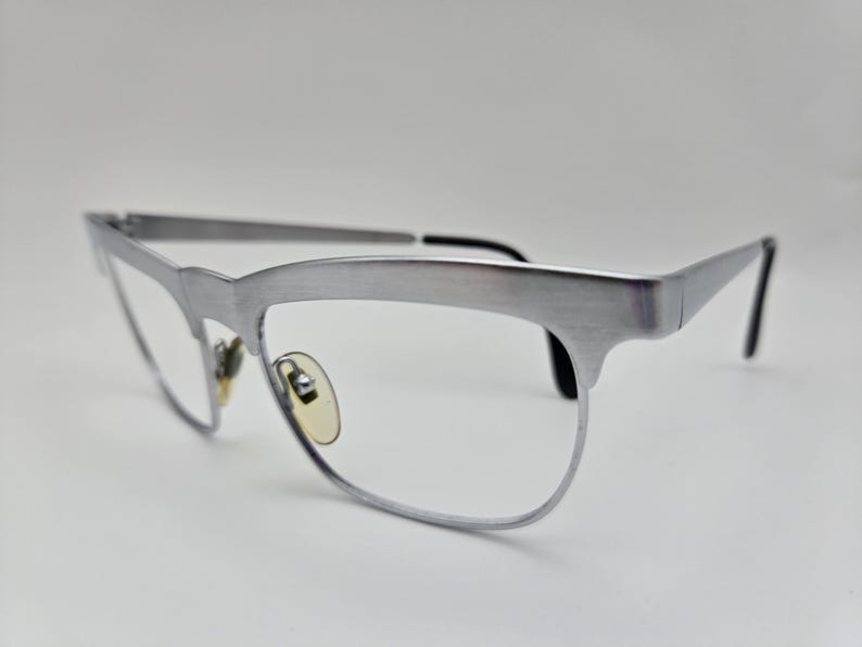 May include: Silver-toned metal eyeglasses with a cat-eye frame and clear lenses.