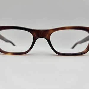 Puede incluir: Un par de gafas de pasta de carey con una montura rectangular clásica.