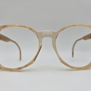 May include: A pair of tortoiseshell spectacles with round lenses and a clear bridge.
