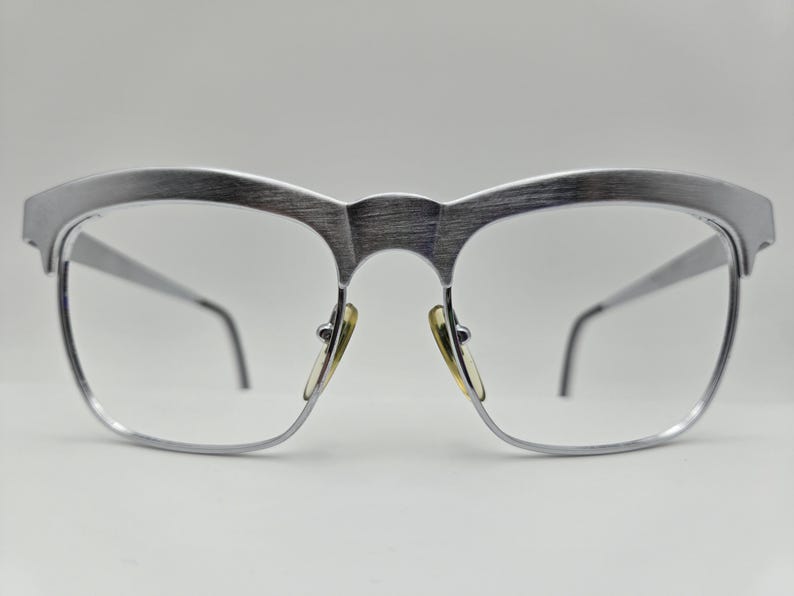 May include: Silver-toned metal eyeglasses with a brushed finish and a rectangular frame.