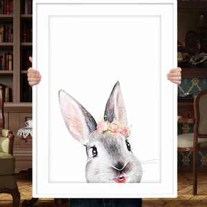 Puede incluir: Una pintura de acuarela de un conejo gris con flores rosas en las orejas. El conejo est&aacute; mirando directamente al espectador con una expresi&oacute;n juguetona.