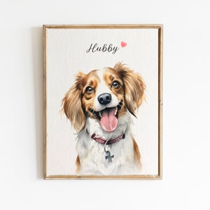 May include: Watercolor painting of a dog with brown and white fur, wearing a burgundy collar with a silver tag. The dog is smiling with its tongue sticking out. The painting is framed in a light wood frame and has the word "Hubby" written in black cursive above the dog with a small red heart.