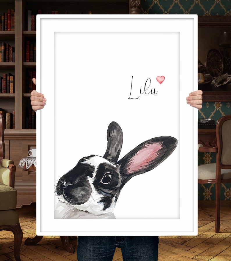 Puede incluir: Una impresi&oacute;n enmarcada en blanco con una pintura de acuarela de un conejo blanco y negro con orejas rosas. El conejo est&aacute; mirando hacia la izquierda. El nombre "Lilu" est&aacute; escrito en cursiva sobre el conejo con un peque&ntilde;o coraz&oacute;n rosa.