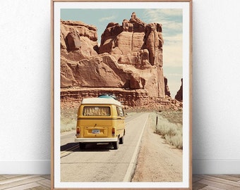 May include: A yellow vintage van drives down a road through a desert landscape with red rock formations in the background.