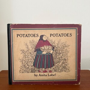 May include: A hardcover book titled Potatoes Potatoes by Anita Lobel. The cover features a central illustration of a person in a dark headscarf, purple shawl, and striped skirt holding a basket of potatoes, set against a background of potato plants.