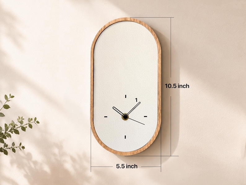 May include: An oval wall clock with a light wood frame and a white face. The clock features black hands and simple black dash markers for the hours. Dimensions are clearly marked as 10.5 inches in height and 5.5 inches in width on the image.