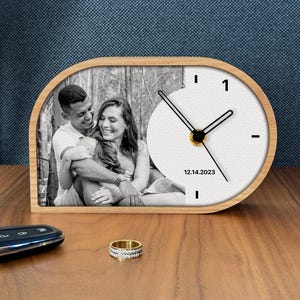 May include: A white ceramic mug with a black handle and the text "But First, Coffee" in a bold, black font. The mug is set against a blurred background, suggesting a cozy setting.