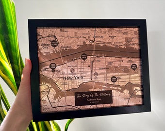 May include: A framed map of New York City with a copper finish. The map is marked with significant locations for a couple, including where they met, their first date, and their first home. The text at the bottom reads "The Story Of The Miller's, Andrea & Ryan, 6.30.2017".
