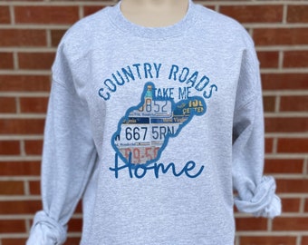 Puede incluir: Sudadera gris con un gráfico azul del estado de Virginia Occidental hecho de placas de matrícula. El gráfico dice "Country Roads Take Me Home".