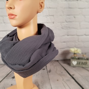 Könnte beinhalten: Ein grauer Schlauchschal aus weichem, strukturiertem Stoff. Der Schal ist um den Hals einer Schaufensterpuppe drapiert und zeigt sein kreisförmiges Design. Der Stoff scheint eine leichte Baumwoll- oder Leinenmischung zu sein, ideal für kühleres Wetter.