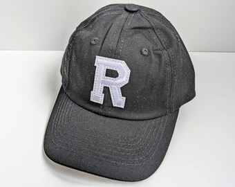 May include: A black baseball cap with a white felt letter 'R' on the front.