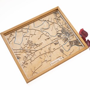 Puede incluir: Un mapa de madera de Bastrop, TX, enmarcado en un marco de madera natural. El mapa está cortado con láser y muestra las calles y las vías fluviales de la ciudad. El mapa es un regalo único y personalizado para cualquiera que ame Bastrop.