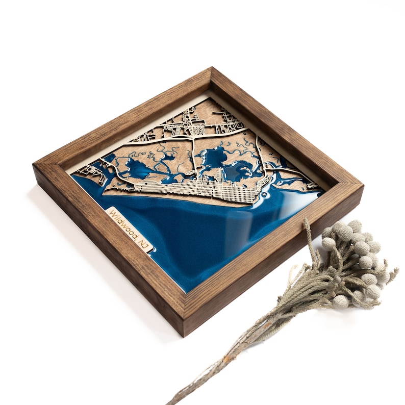 A wooden map of your favourite place enclosed in a wooden frame. It has 3D city streets and epoxy resin water. By adding a pin in a important place for you and an engraving you will make a personalized gift.