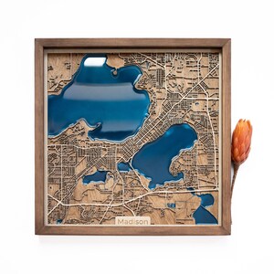 A wooden map of your favourite place enclosed in a wooden frame. It has 3D city streets and epoxy resin water. By adding a pin in a important place for you and an engraving you will make a personalized gift.