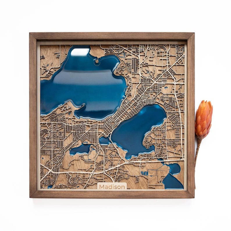 A wooden map of your favourite place enclosed in a wooden frame. It has 3D city streets and epoxy resin water. By adding a pin in a important place for you and an engraving you will make a personalized gift.