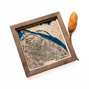 May include: A wooden map of Barranquilla, Colombia, with a blue resin river and a brown wooden frame.