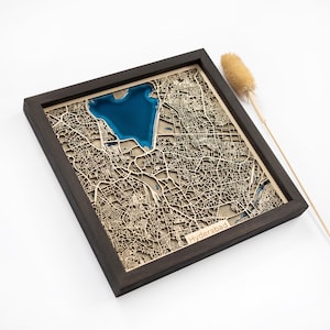 May include: A wooden map of Hyderabad, India, with a blue lake in the center. The map is framed in a dark wood frame and the city name is printed below the map.