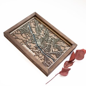 A wooden map of your favourite place enclosed in a wooden frame. It has 3D city streets and epoxy resin water. By adding a pin in a important place for you and an engraving you will make a personalized gift.