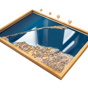 Peut inclure: Une carte en bois d'une zone côtière avec un incrustation de résine bleue représentant l'eau. La carte est encadrée dans un cadre en bois naturel.