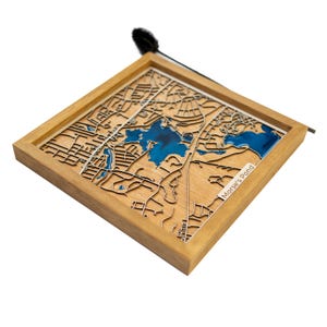 Puede incluir: Un mapa de madera de Morse's Pond con una incrustación de resina azul para el agua. El mapa está enmarcado en un marco de madera natural.