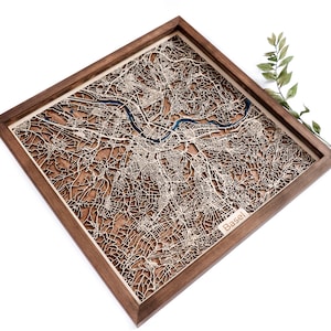 Peut inclure: Une carte en bois de Bâle, en Suisse, dans un cadre en noyer. La carte est découpée au laser et montre les rues et les cours d'eau de la ville. Le nom de la ville est gravé dans le coin inférieur droit.