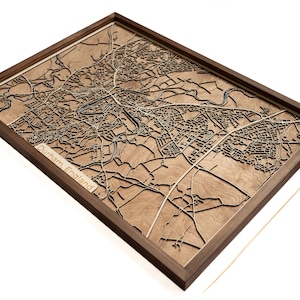 Puede incluir: Un mapa de madera de Durham, Inglaterra, en un marco de nogal. El mapa está cortado con láser y muestra las calles y los puntos de referencia de la ciudad. El mapa está montado sobre una base de madera y tiene un acabado marrón.