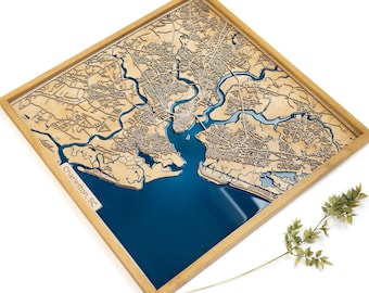 May include: A wooden map of Charleston, South Carolina, with a blue resin inlay representing the water. The map is framed in a natural wood frame and includes the text "Charleston, SC".